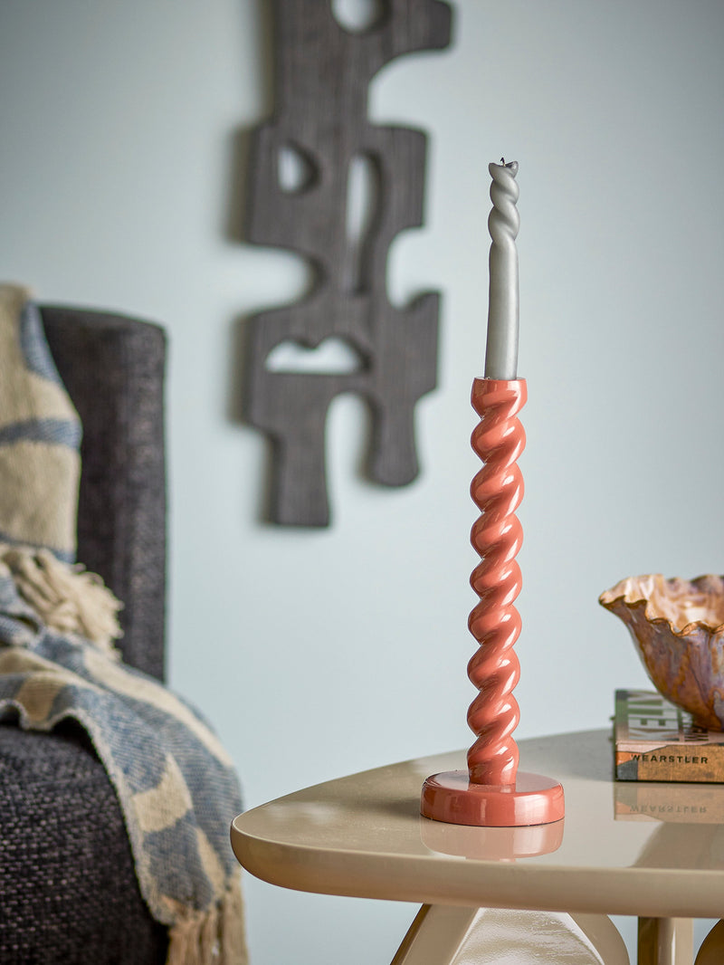 brown spiral diza candle holder with grey taper candle on side table
