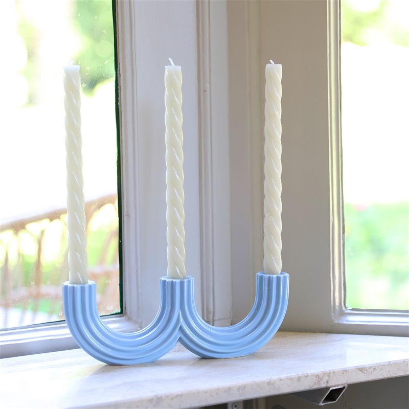 Light blue Churros candle holder with two cream taper candles on a sunny windowsill
