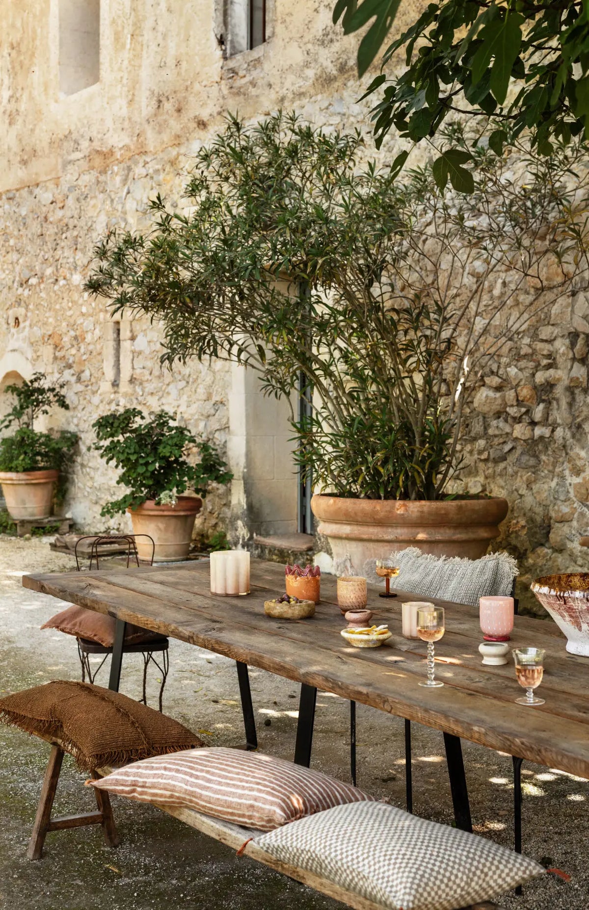 Clara votives by Olsson & Jensen on a long outdoor dining table in a sunny courtyard