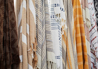 Close-up of hanging throws including warm honey and ecru striped recycled cotton design