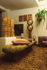 Daisy camel cushion by Olsson & Jensen on a textured daybed in a retro living room