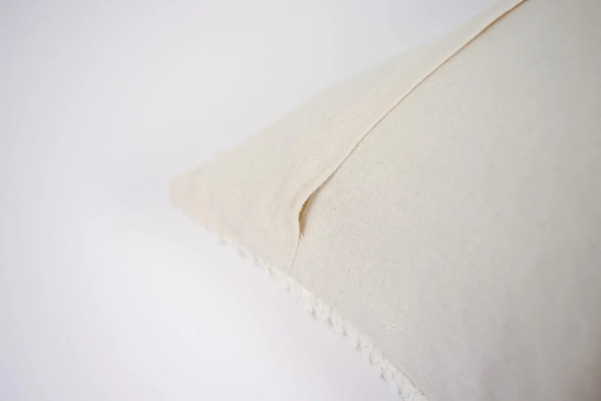 Edge detail of the Elba cream cotton cushion by Olsson & Jensen showing the plain cotton back