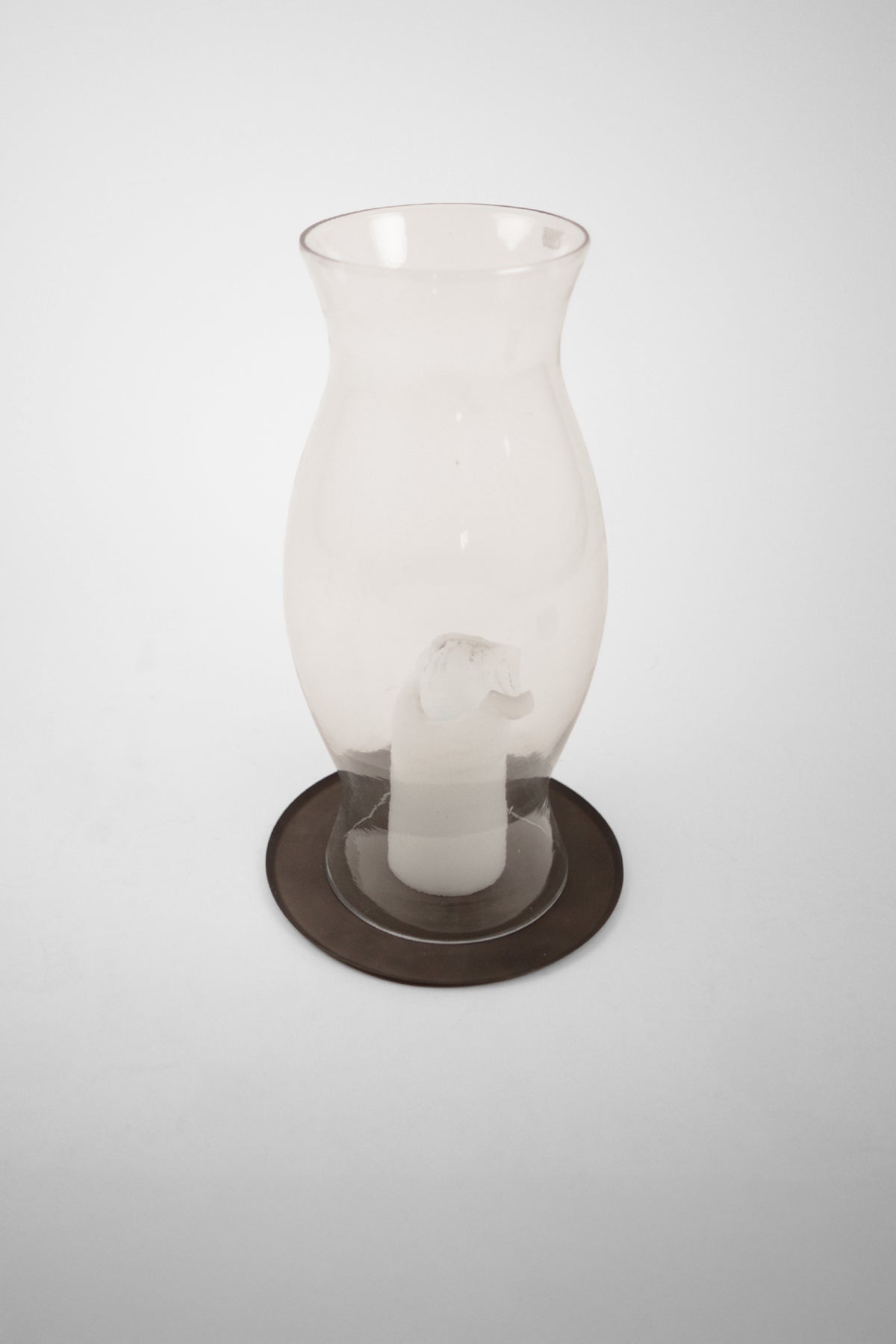 Elia candle plate by Olsson & Jensen under a glass hurricane lantern with a candle