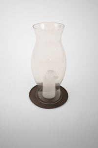 Elia candle plate by Olsson & Jensen under a glass hurricane lantern with a candle