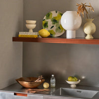 Speckled footed bowls styled in a kitchen with lemons on a steel worktop