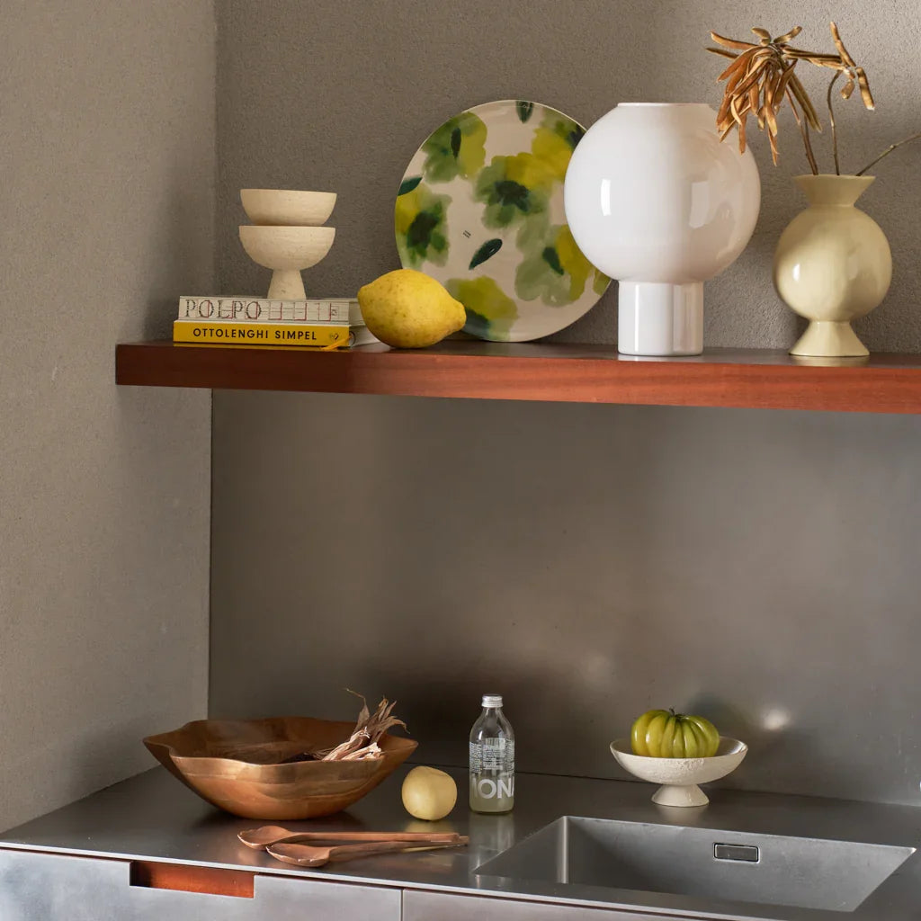 Speckled footed bowls styled in a kitchen with lemons on a steel worktop