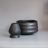 graphite chasen naoshi matcha whisk stand with metallic speckles beside matching bowl
