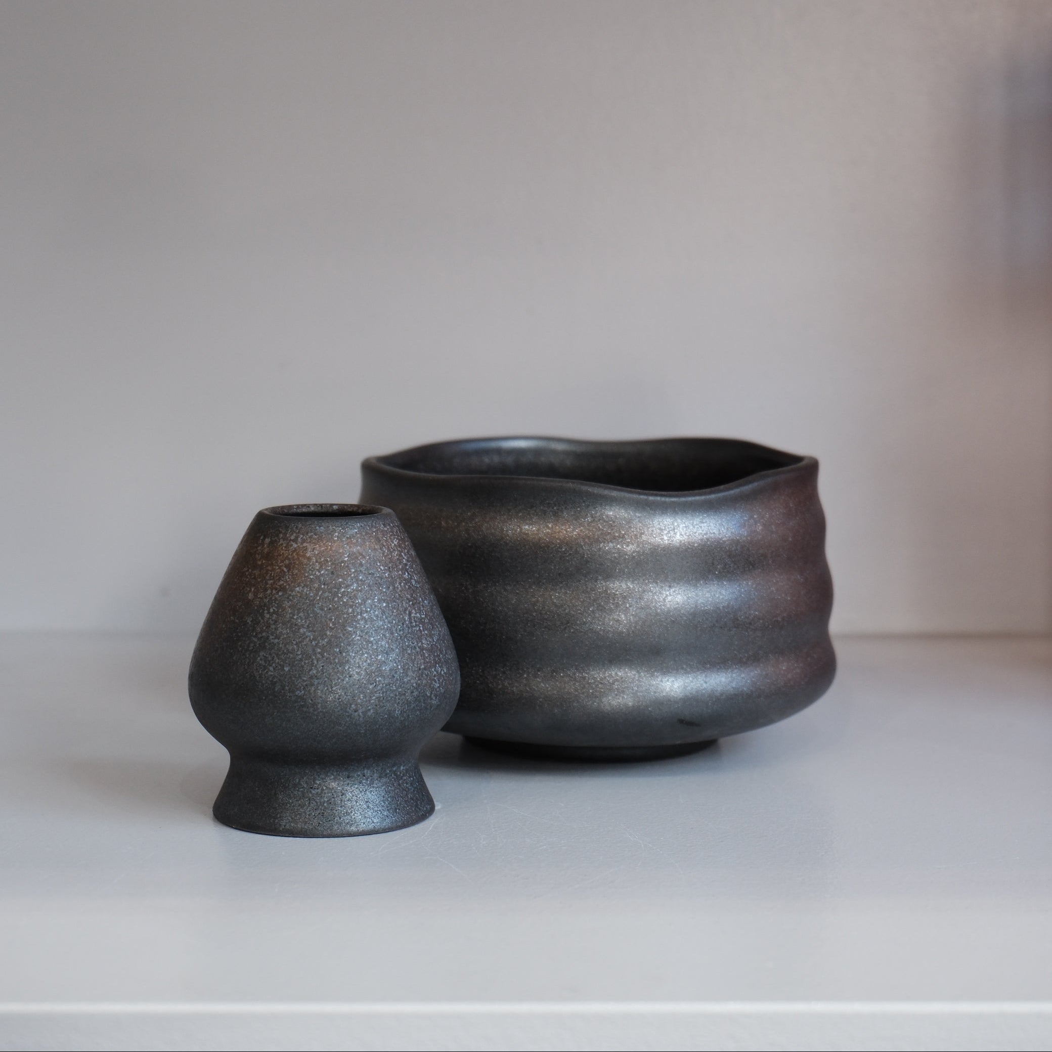 graphite chasen naoshi matcha whisk stand with metallic speckles beside matching bowl
