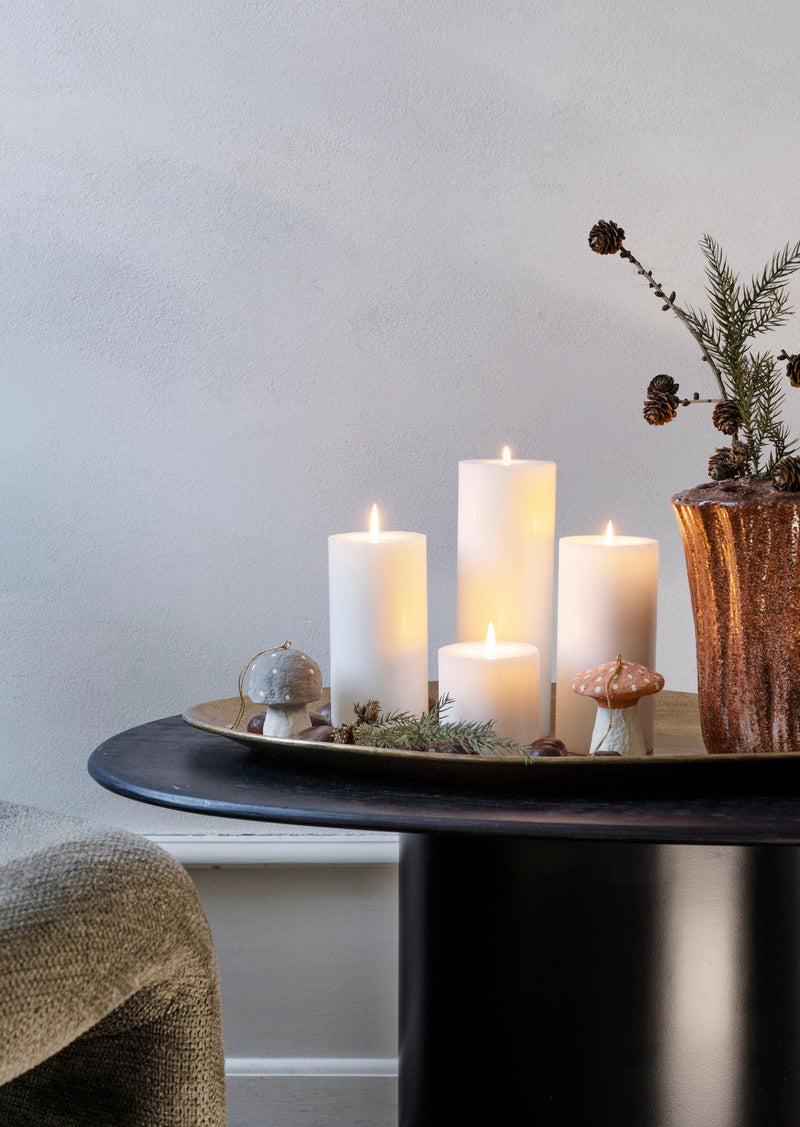 hand hammered oval brass tray styled with candles on a dark round table
