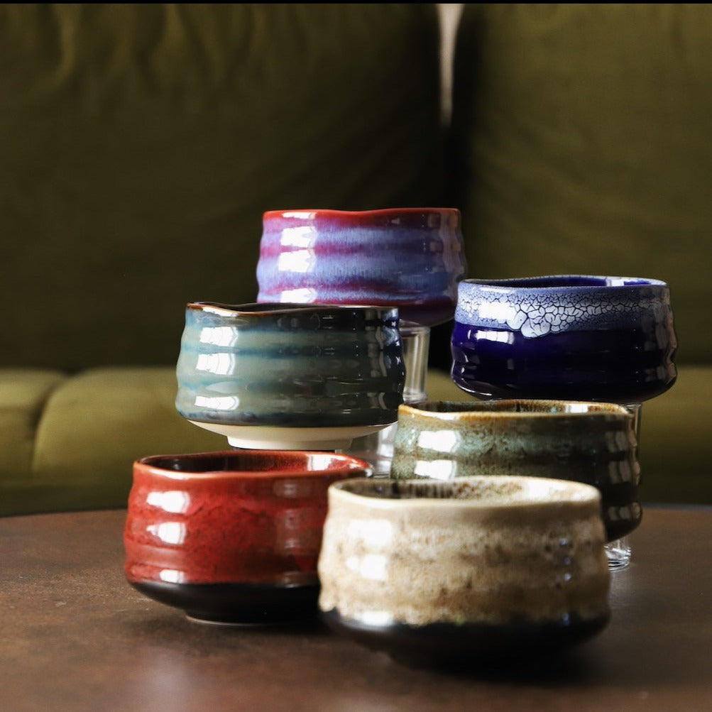 Handmade matcha bowls in a range of glazes including red lava, grouped on a table