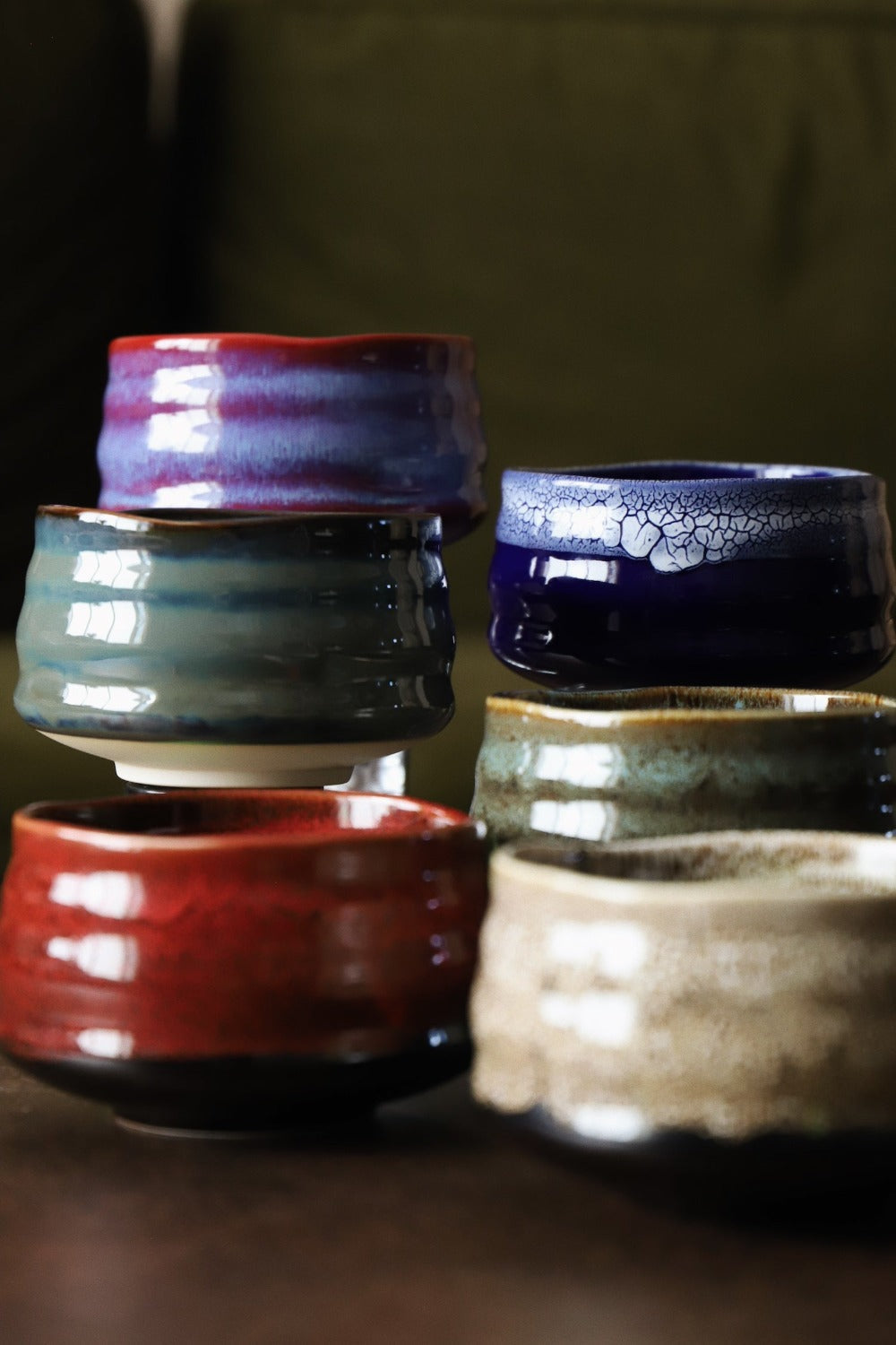 Red lava matcha bowl in front of a group of handmade matcha bowls in mixed glazes