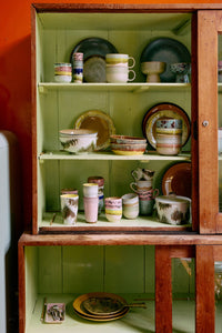 70s ceramics café cups and tableware styled on green shelves with retro colour accents
