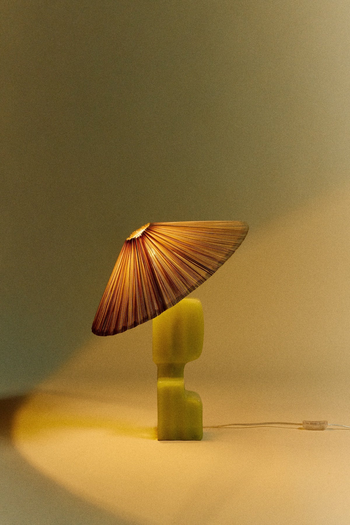 ivory pleated lampshade by HKLIVING lit on a sculptural green lamp base for warm ambient lighting