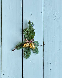 House Doctor gold acorn decorations tied to a pine sprig on a pale blue painted wooden door
