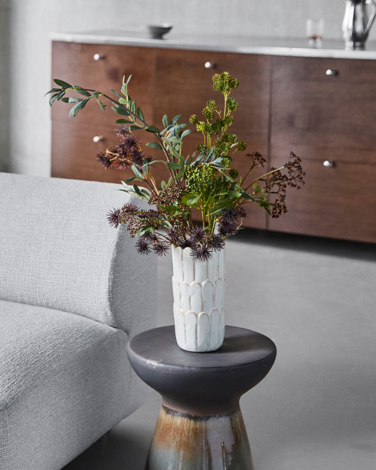 House Doctor Ezra off-white petal vase with autumn stems on a dark side table