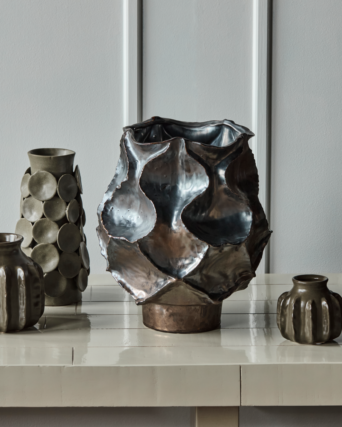 House Doctor Waves large statement vase styled alongside the Dot vase and smaller handmade stoneware ceramics on a pale console, a sculptural tonal grouping for modern interiors