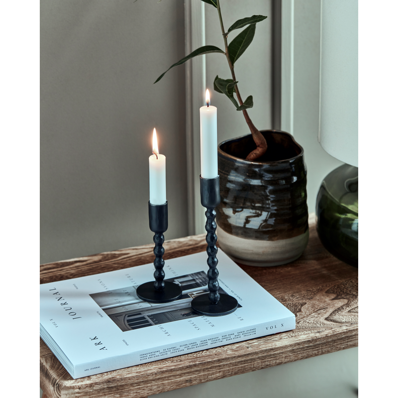 pair of house doctor mala candle holders with taper candles lit
