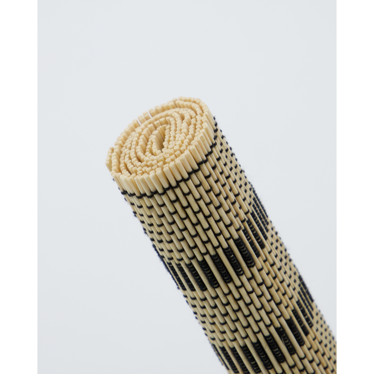 Rolled black and beige bamboo placemat showing woven texture
