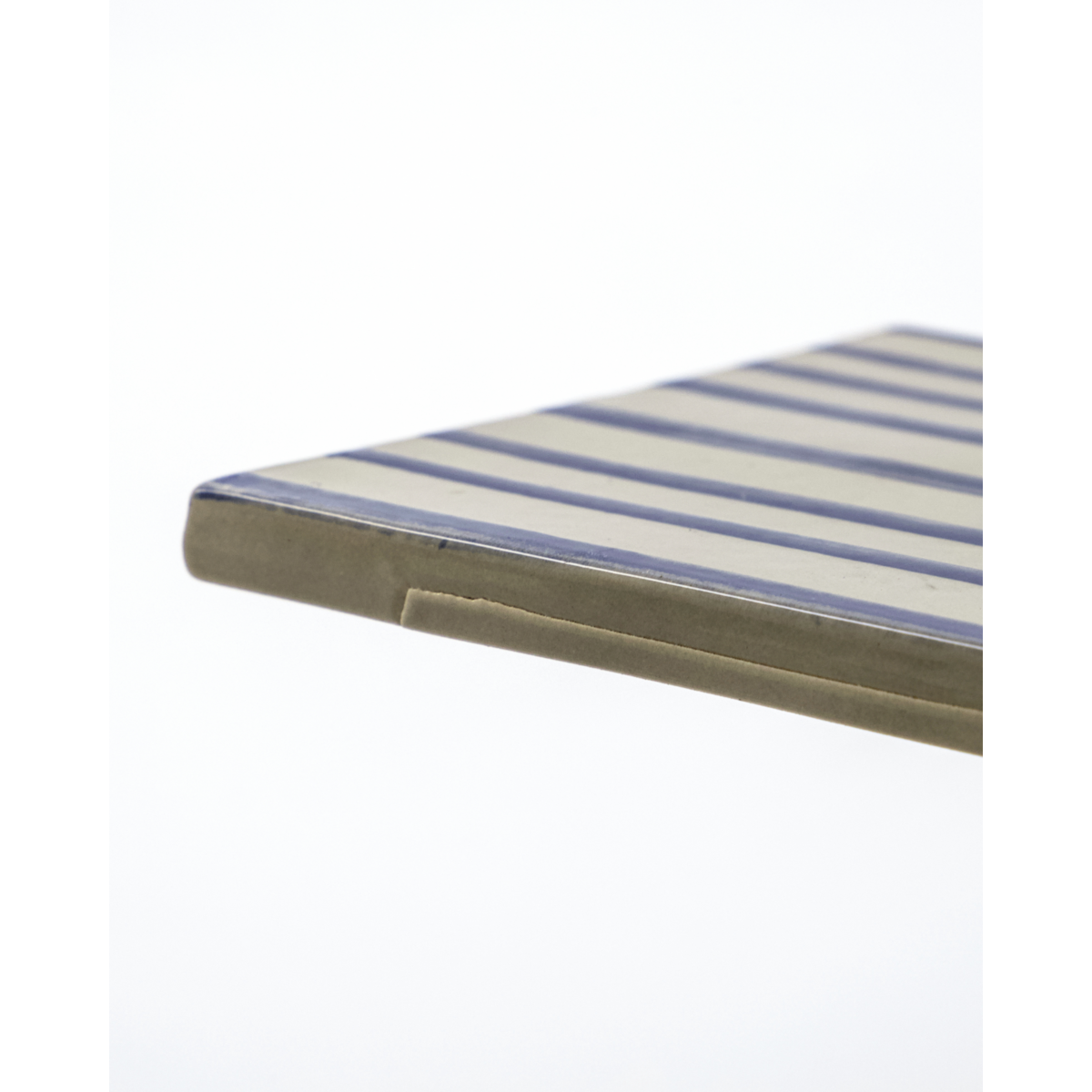 Edge detail of hand-painted ceramic board in blue and beige
