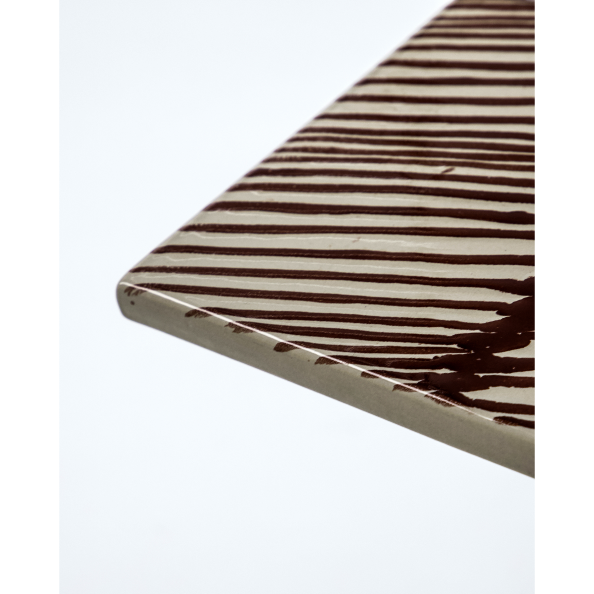 Detail of brown striped ceramic board showing edge and brushstroke glaze
