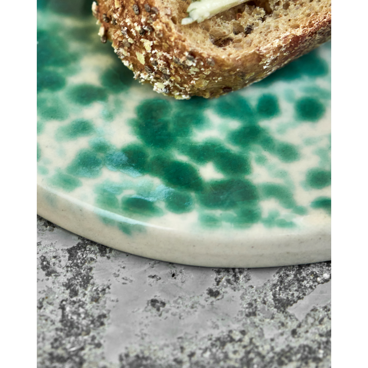 Close-up of glossy green splash glaze on ceramic plate
