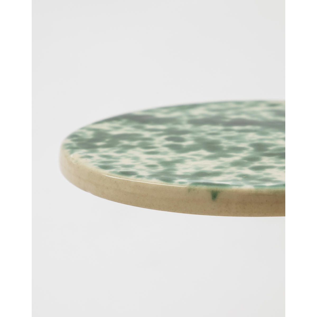 Edge view of round green stoneware board with hand-glazed finish
