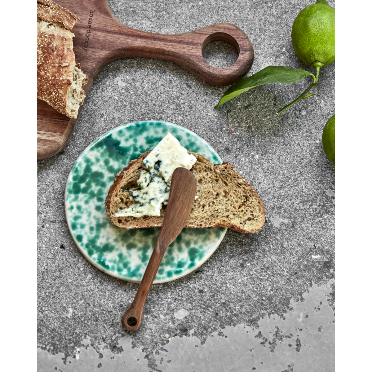 Green glazed ceramic board styled with cheese and bread

