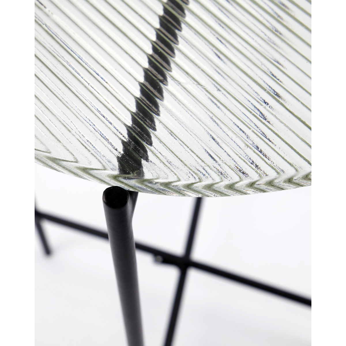 Diagonal close-up of the ribbed glass tabletop and slender leg frame of the House Doctor Tamu table

