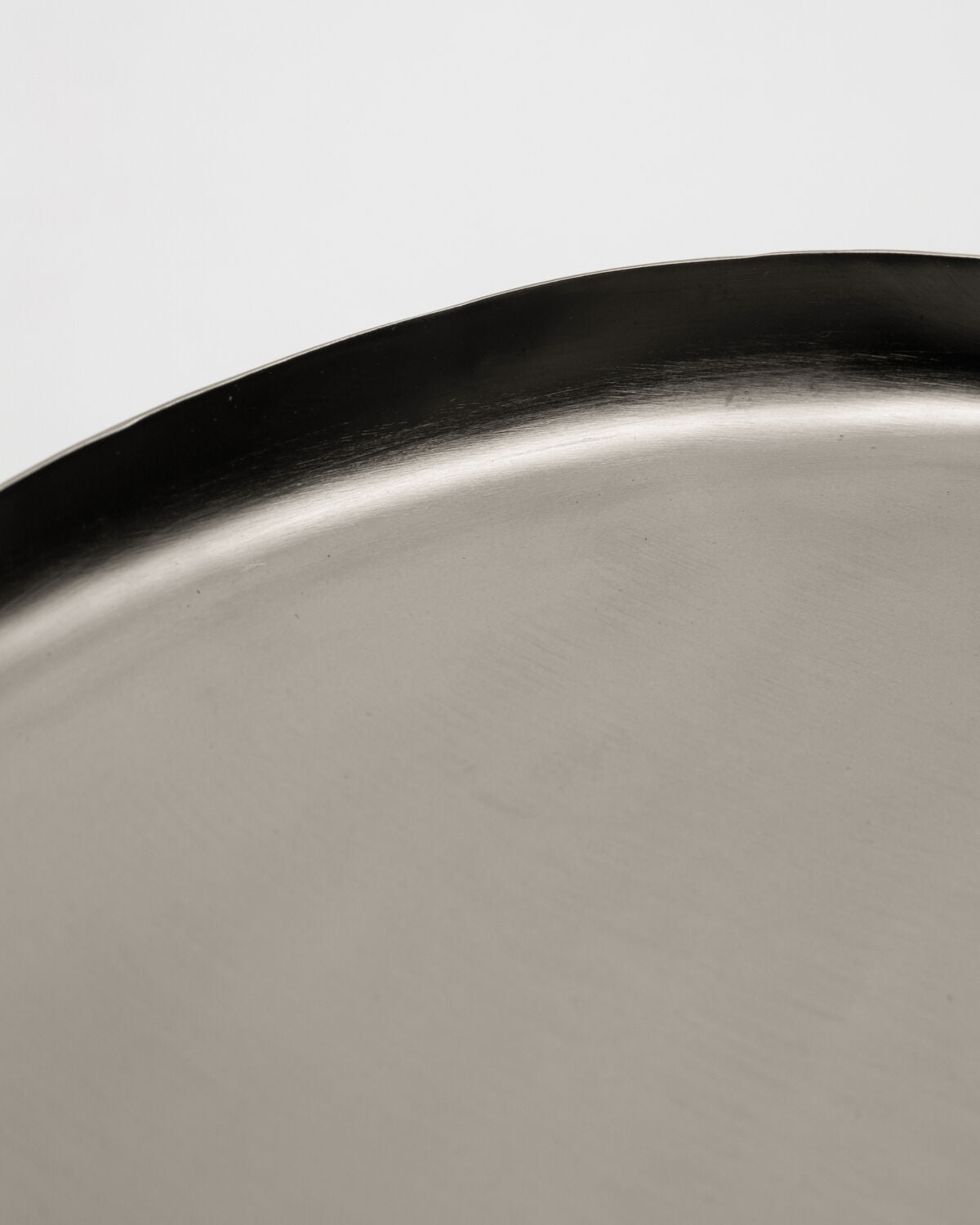 Close-up of the House Doctor Osea Tray's brushed silver metal finish and wavy rim edge