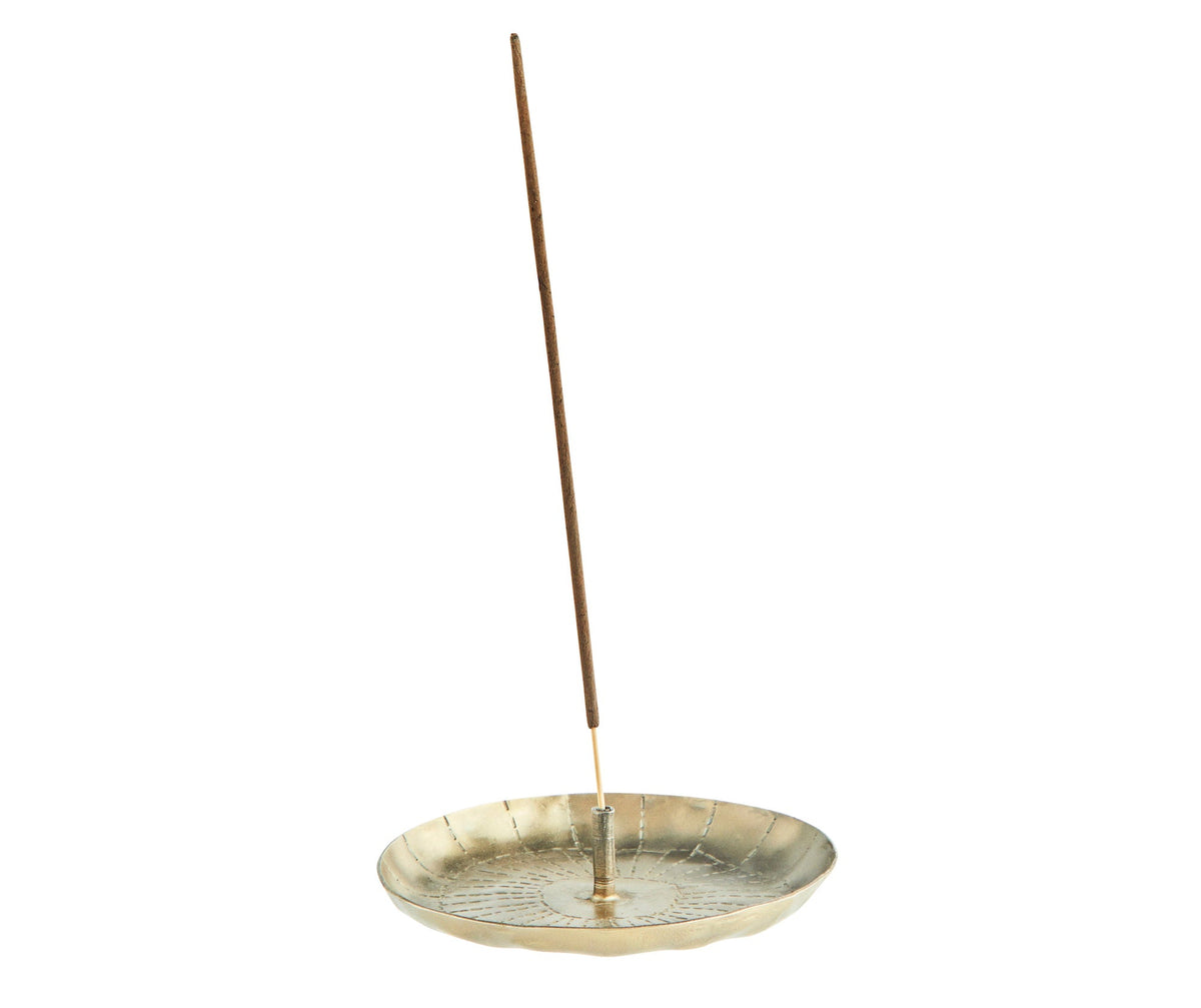 close up of iron incense holder in antique brass holding incense stick
