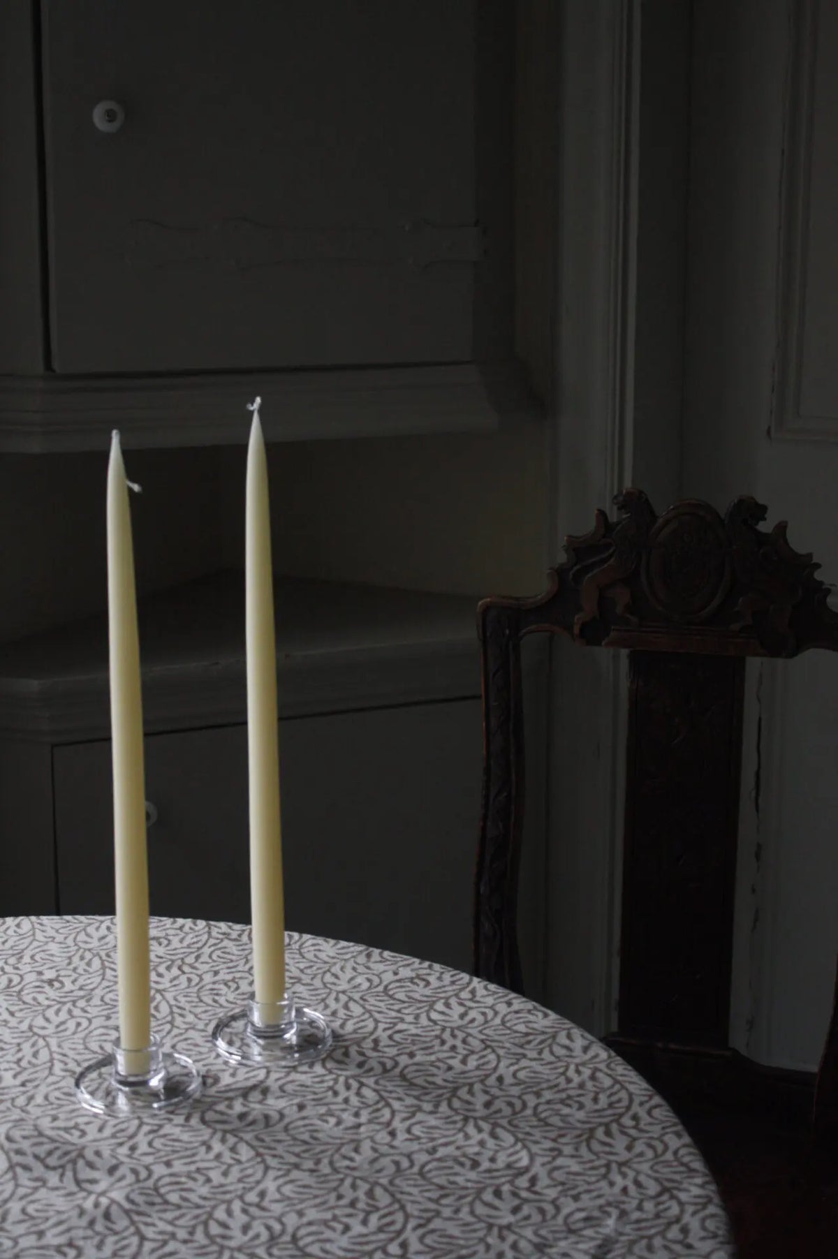 Isabella glass candle holders by Olsson & Jensen with tall taper candles on a dark dining table
