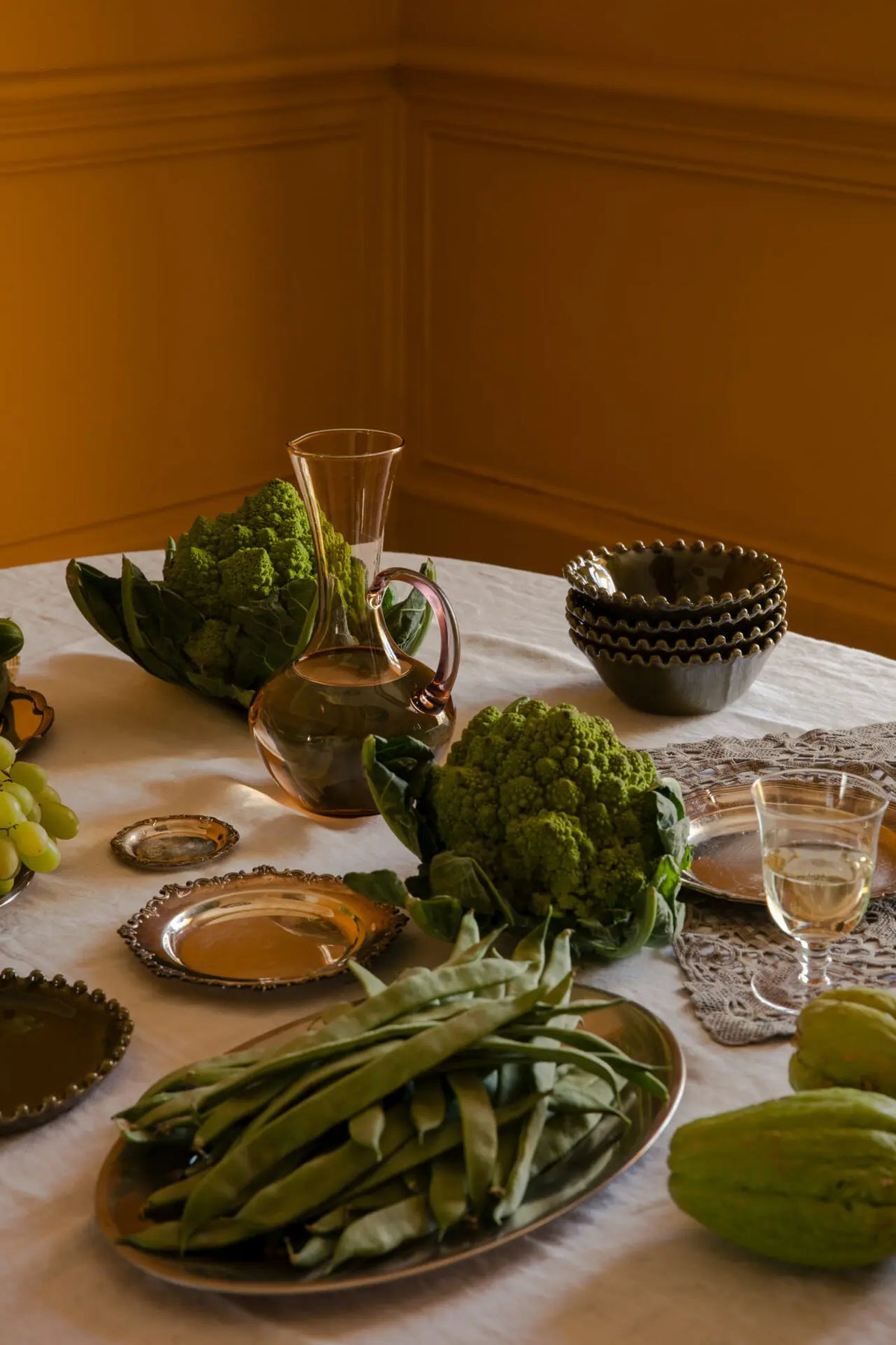 Isidora glass jug by Olsson & Jensen on a candlelit dinner table set with seasonal vegetables and tableware