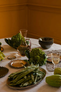 Isidora glass jug by Olsson & Jensen on a candlelit dinner table set with seasonal vegetables and tableware