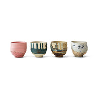 Set of four ceramic cups with unique designs on a white background