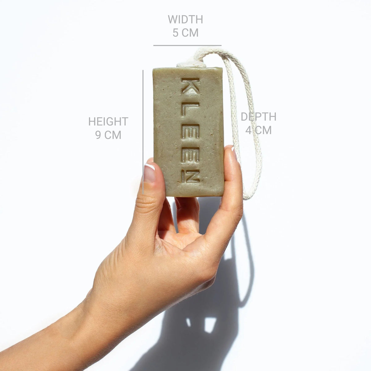 Hand holding the KLEEN Woodstock soap bar with dimensions marked to show its size
