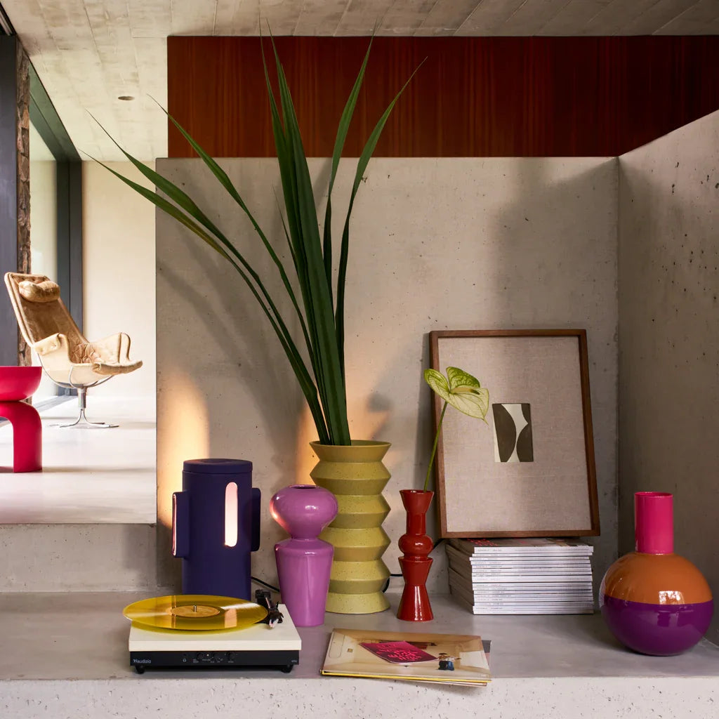 Pale lime Kova vase with palm leaves styled among colourful ceramics and framed art