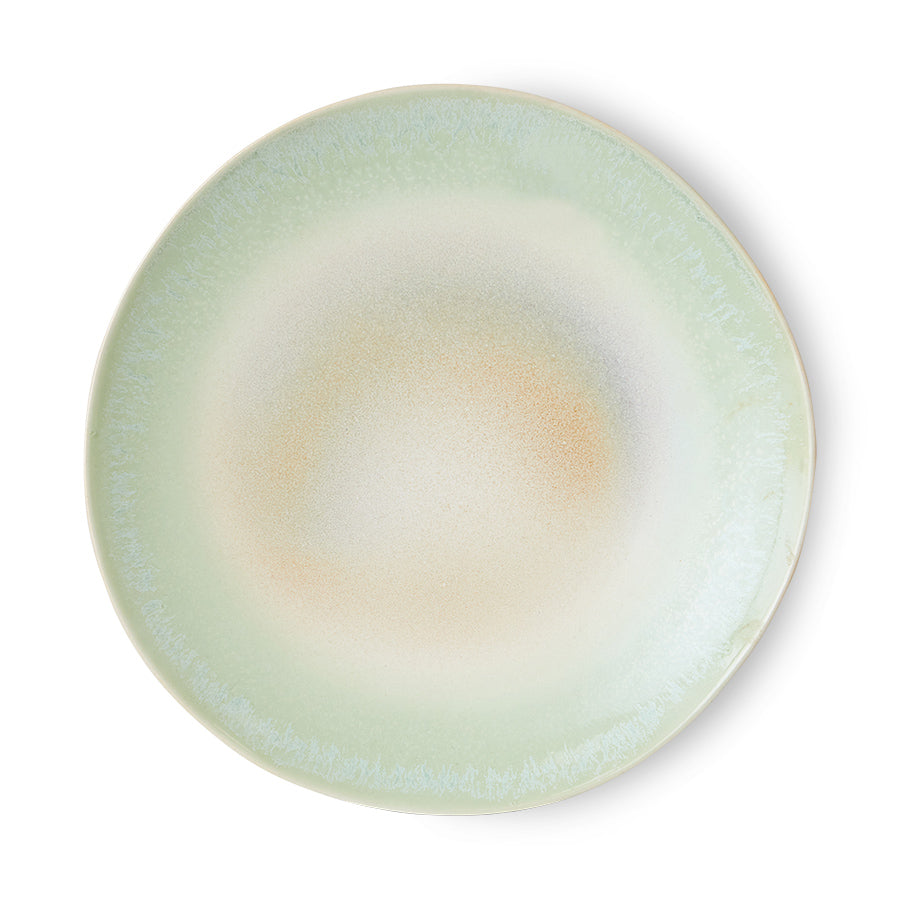 Round ceramic plate with a gradient color from green to beige on a white background