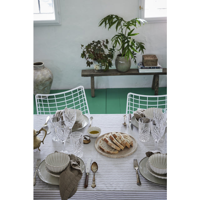 Ellia beige marble tray holding bread on a laid dining table with striped tablecloth