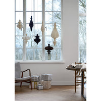 Passia honeycomb paper ornaments in off white and dark colours hanging at different heights in a large window