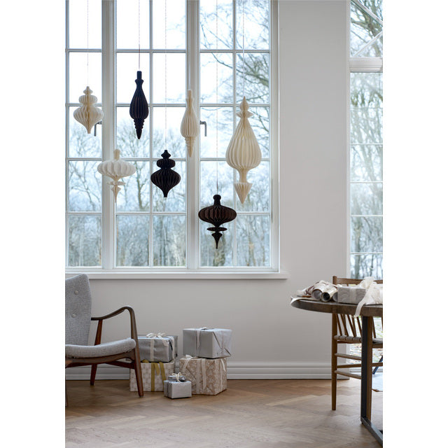 Passia honeycomb paper ornaments in off white and dark colours hanging at different heights in a large window