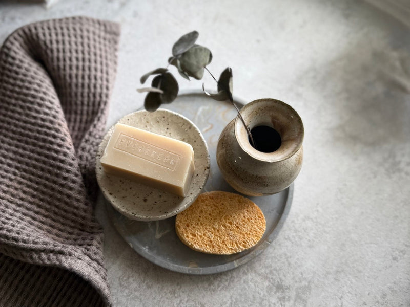Soap dish styled in calm bathroom setting with eucalyptus and natural sponge