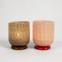 Lit Lolo pink tealight holder by Olsson & Jensen beside an amber holder