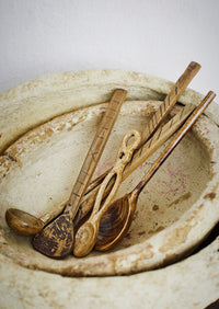 hand-carved mango wood serving spoon styled in rustic bowl with other wooden utensils