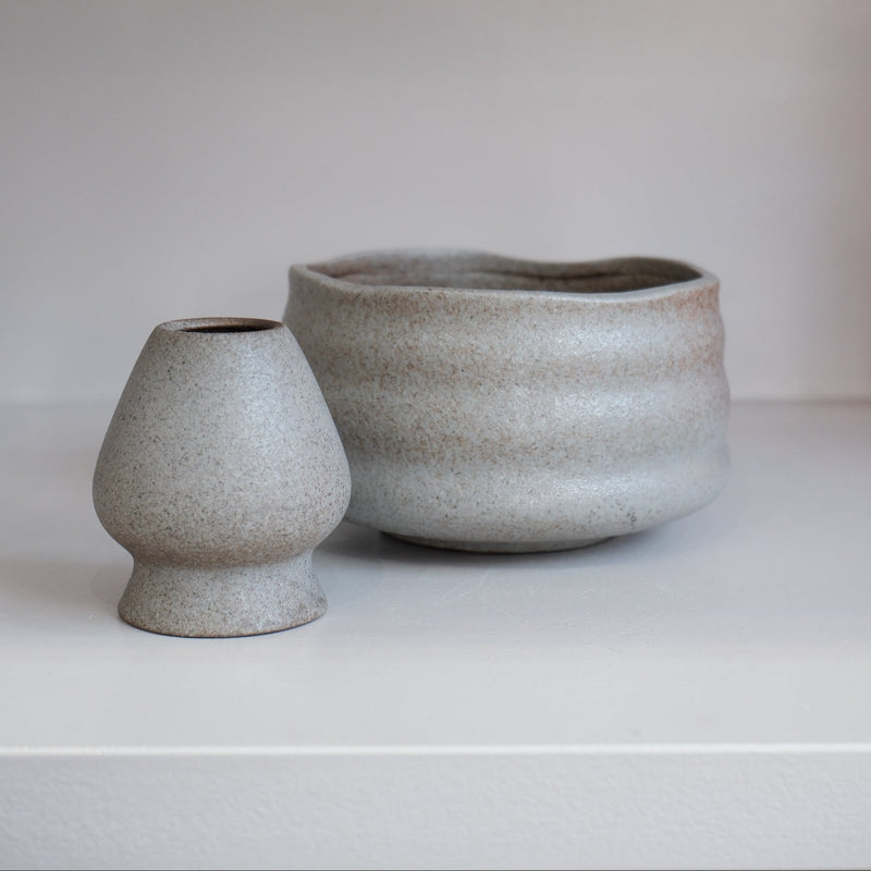 pebble grey matcha bowl with brown speckles alongside matching ceramic whisk holder