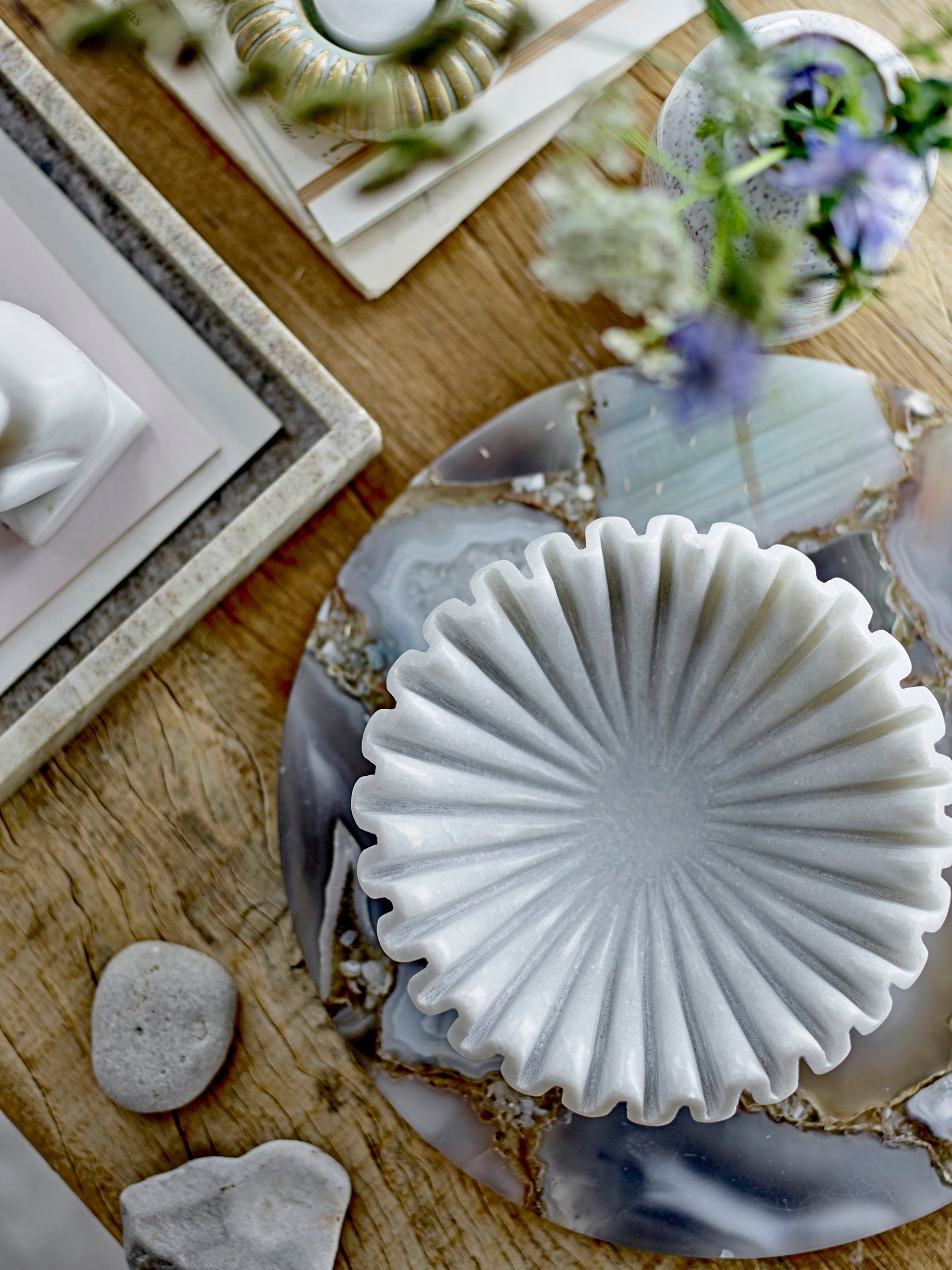 Modern wave form marble decorative dish catching soft light on wooden shelf