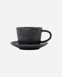 Minimalist stoneware cup and saucer in black and brown tones.