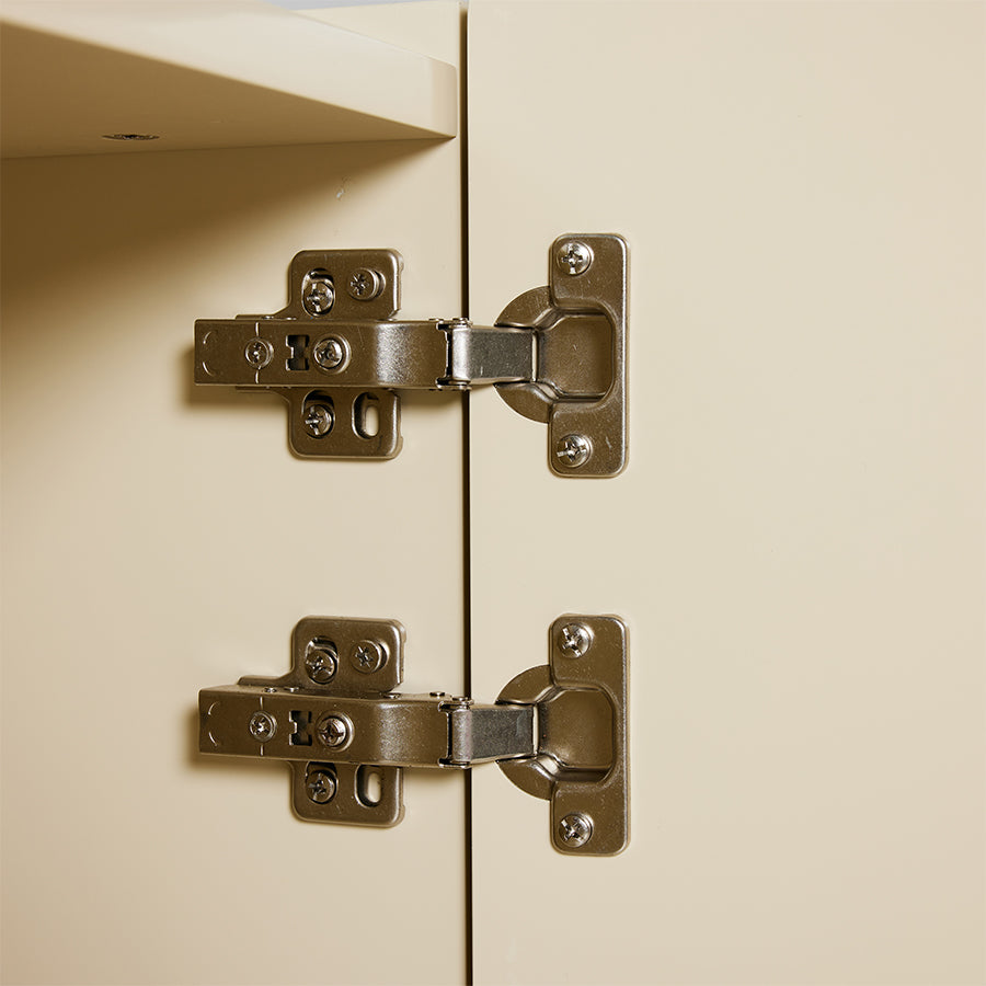 Close-up of cabinet hinges on a beige cabinet door