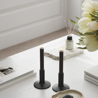 Mocha LED dinner candles on a chair by the window, styled with books and red berry stems for a warm, hygge feel.
