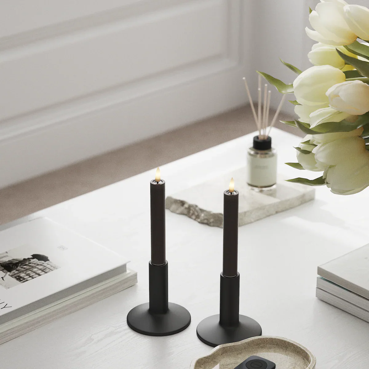 Mocha LED dinner candles on a chair by the window, styled with books and red berry stems for a warm, hygge feel.
