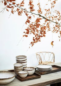 rustic Nordic table setting with stacked speckled stoneware bowls and plates
